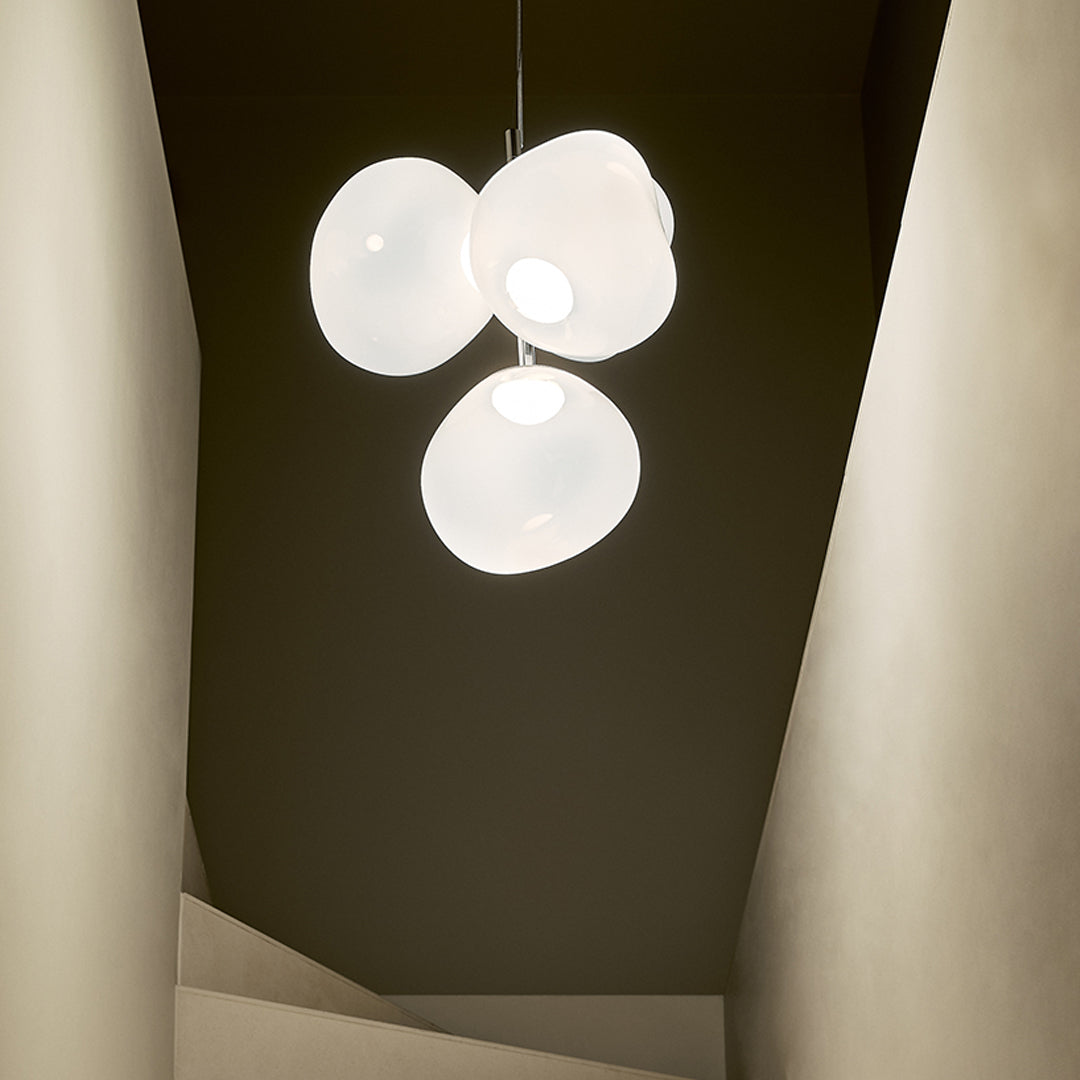 Contemporary white pendant light with smooth, rounded shapes, set against a dark, minimal backdrop.