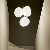 Contemporary white pendant light with smooth, rounded shapes, set against a dark, minimal backdrop.