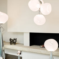 Elegant white spherical pendant lights with glossy finishes, set against a minimalist neutral backdrop.