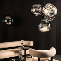 Modern pendant light featuring chrome and glass globes against a textured dark wall, complemented by light beige furnishings.