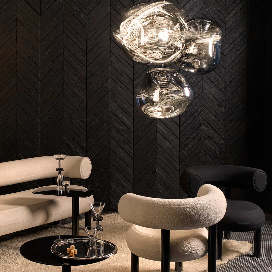 Modern living space with black and white furniture, metallic light fixture, and textured dark wood wall.