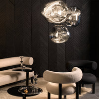 Modern living space with black and white furniture, metallic light fixture, and textured dark wood wall.