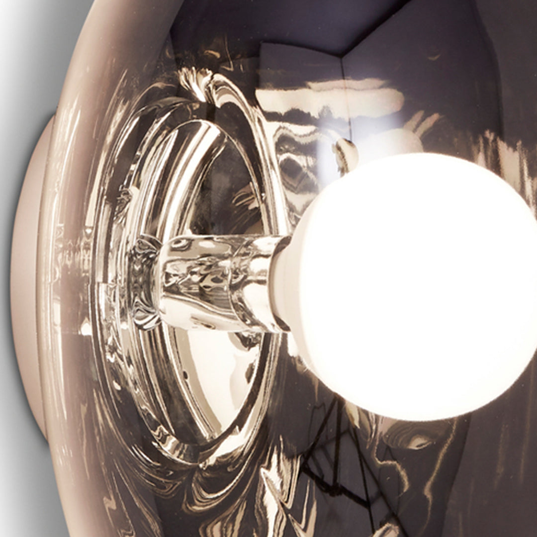 Modern clear glass lampshade with a sleek, reflective finish and a soft white bulb. Elegant minimalist design.