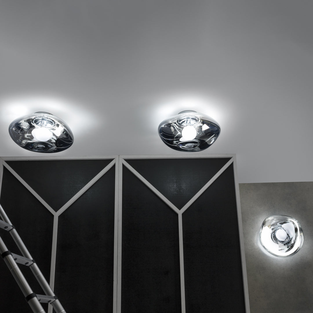 Chrome ceiling lights with modern, geometric patterns against a sleek, dark wall. Bright illumination accents design.
