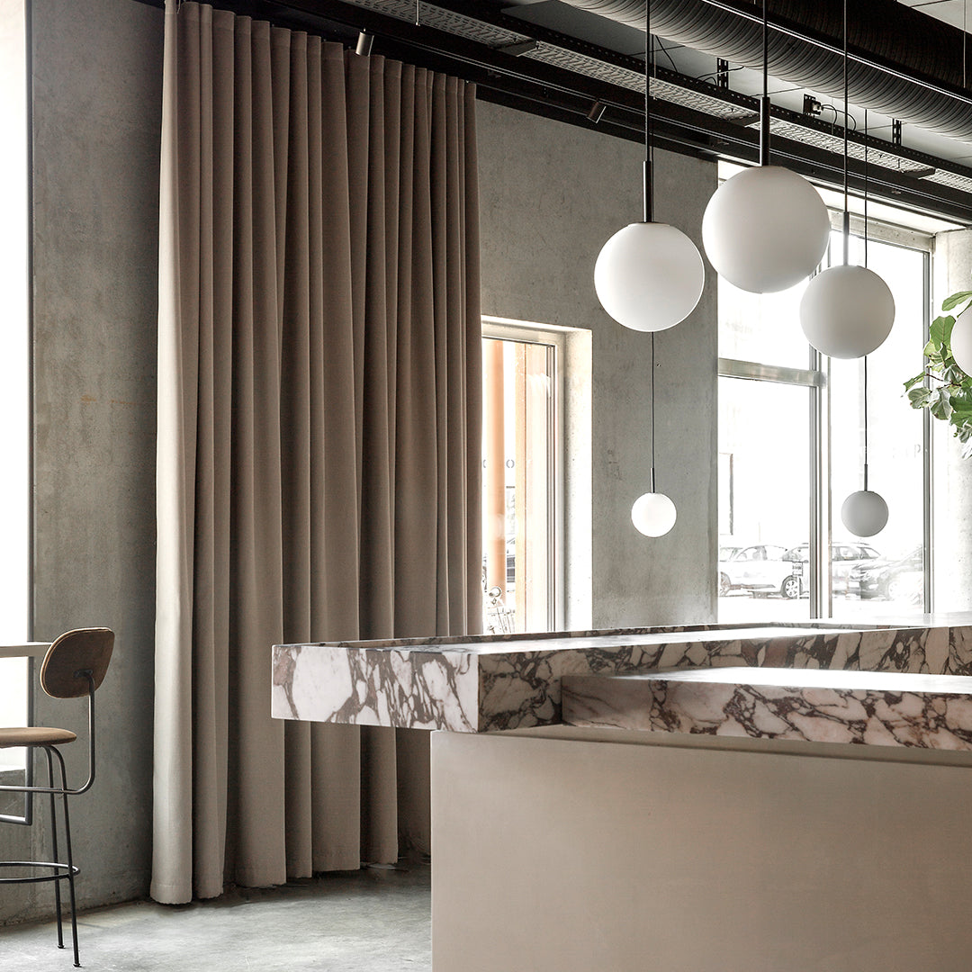 Beige curtains drape gracefully, paired with a sleek marble countertop in soft gray and white tones. Modern lighting accents add elegance.