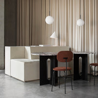 Modern dining area with beige curtains, white furniture, black table legs, and a brown velvet chair. Elegant color palette.