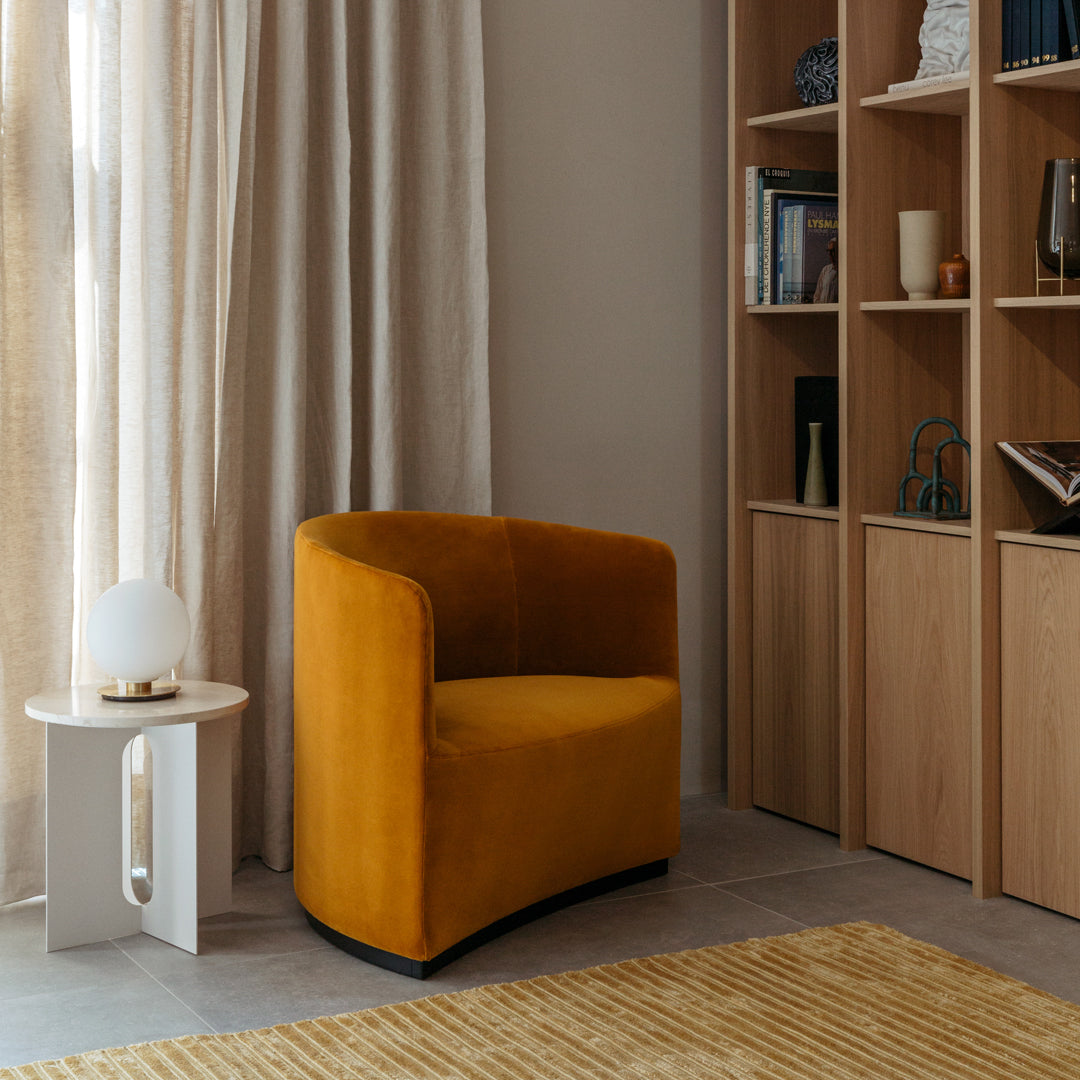 "Stylish mustard yellow accent chair with a smooth, curved design set against a neutral backdrop and natural textures."