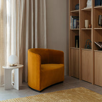 "Stylish mustard yellow accent chair with a smooth, curved design set against a neutral backdrop and natural textures."