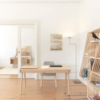 Wooden desk with natural finish, minimalist design, beige and light wood tones, complemented by soft, neutral wall colors.