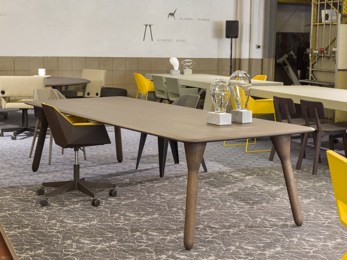 Stylish gray dining table with wooden legs, surrounded by yellow and neutral-toned chairs on a textured carpet.