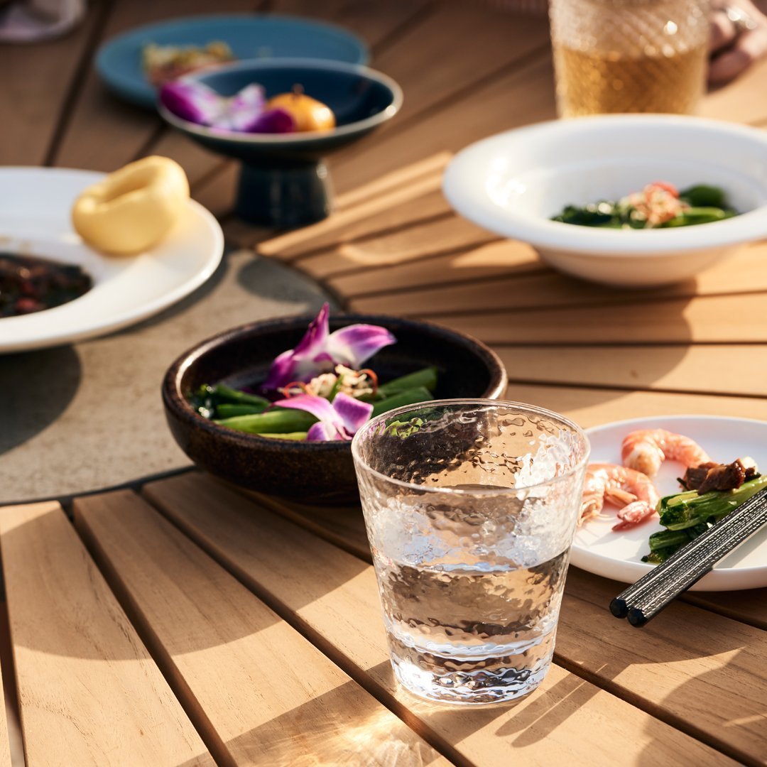 Elegant table setting featuring colorful dishes, vibrant purple orchids, and earthy wooden textures.