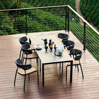"Modern black and wood dining set on a wooden deck, surrounded by lush greenery."
