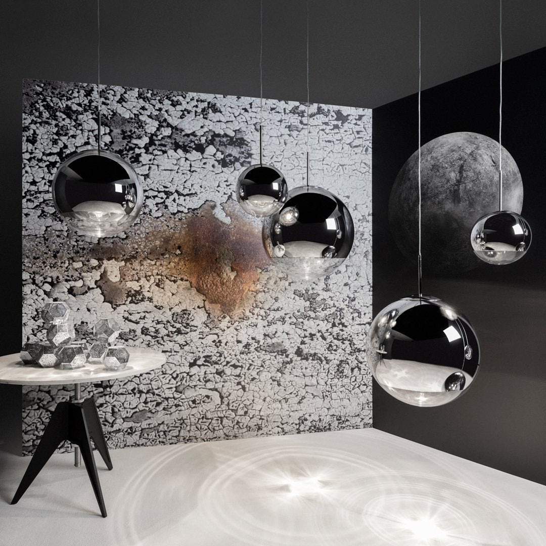 Modern black and silver pendant lights against a textured black and white backdrop with abstract patterns.