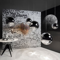 Modern black and silver pendant lights against a textured black and white backdrop with abstract patterns.