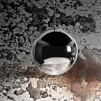 Reflective black and silver spherical pendant light against a textured gray and rusty backdrop, modern industrial style.