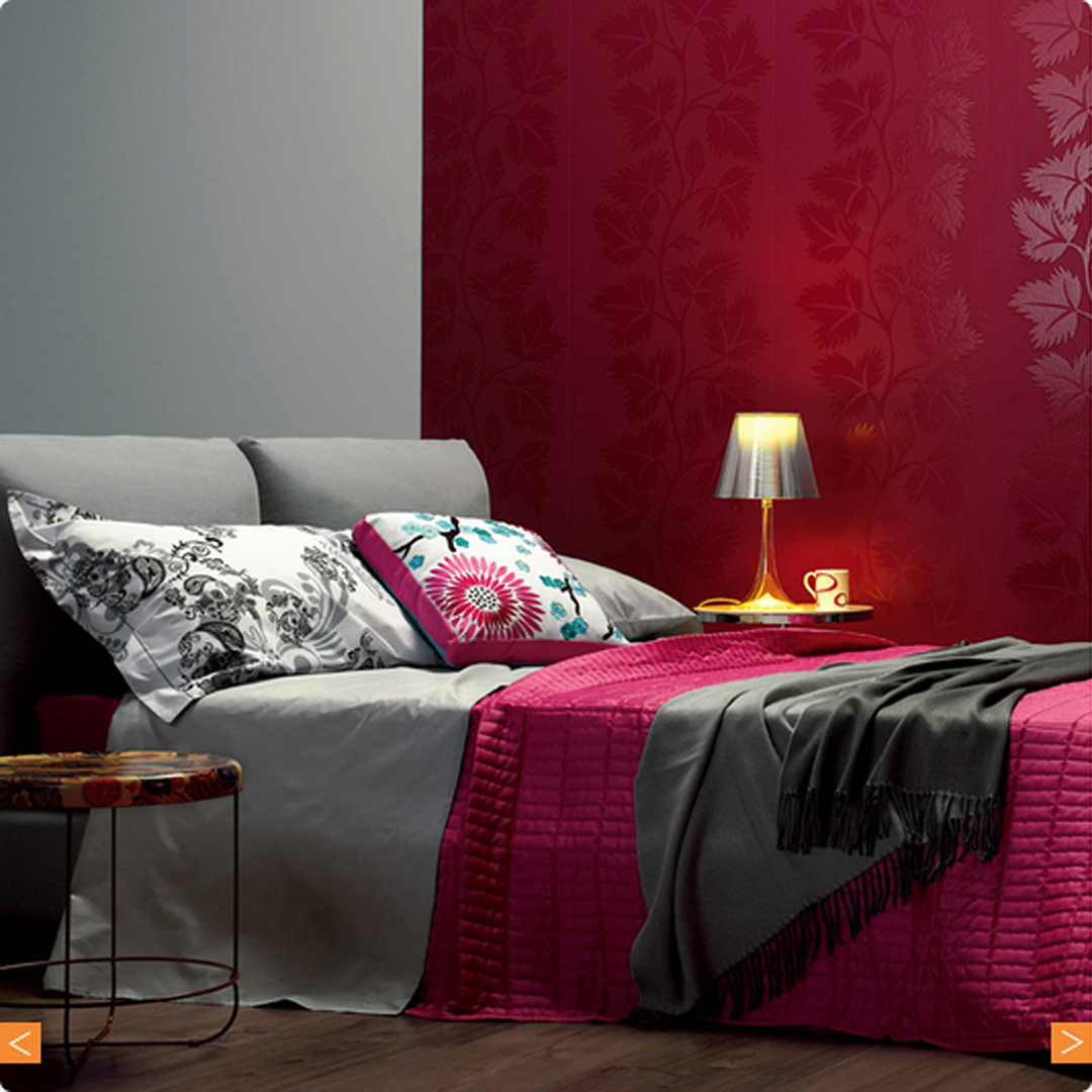 Vibrant red and gray bedding with floral patterns, complemented by colorful accent pillows and stylish decor.