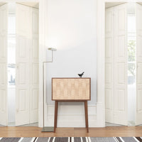 Wooden cabinet with a beige geometric pattern and dark brown legs, set against a bright white wall.