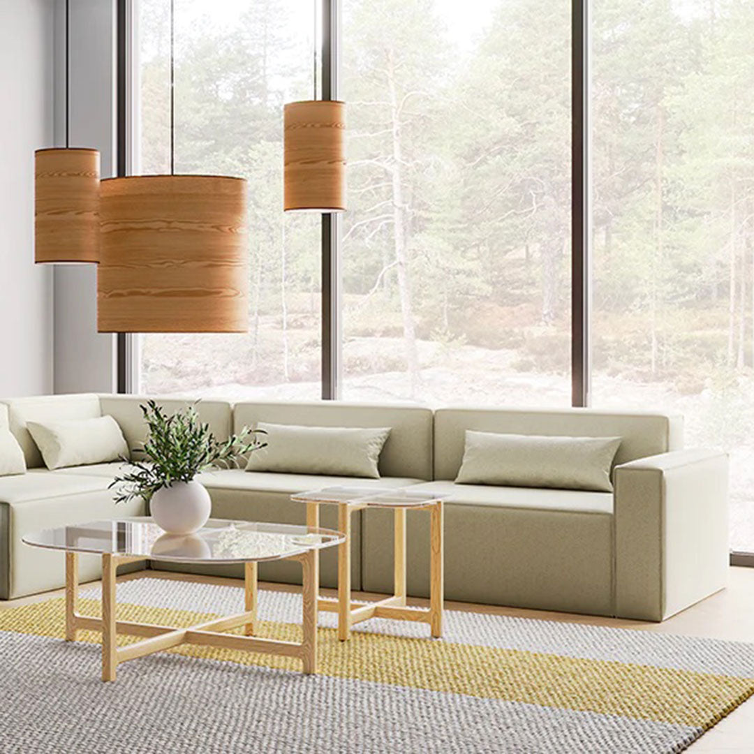 Light green sofa with neutral pillows, natural wood accents, and a geometric patterned rug in serene indoor setting.