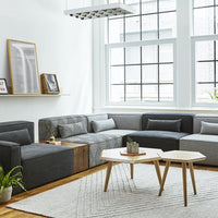 Modern sectional sofa in gray tones with a textured pattern, complemented by a light area rug and wooden accents.