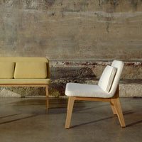 Two modern chairs featuring soft yellow and white upholstery against a rustic concrete backdrop.