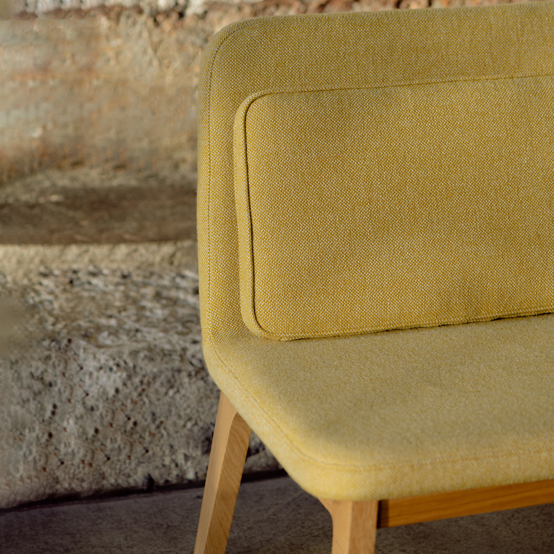 Yellow upholstered chair with a smooth finish, featuring a solid block color and minimalist design.