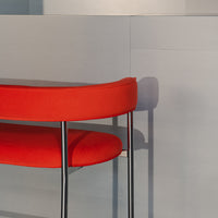 Vibrant red curved chair with sleek gray background and minimalist design. Perfect for modern decor.