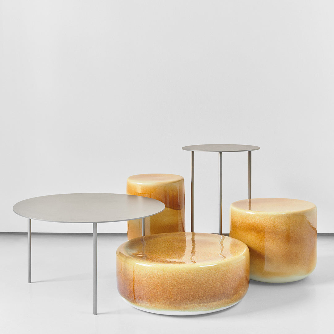 Set of four modern tables featuring smooth, glossy amber and cream colors with sleek metal legs.