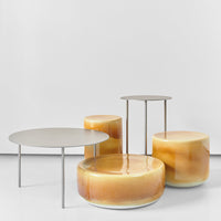 "Modern coffee tables in amber and soft beige, featuring smooth, rounded shapes and sleek metallic legs."