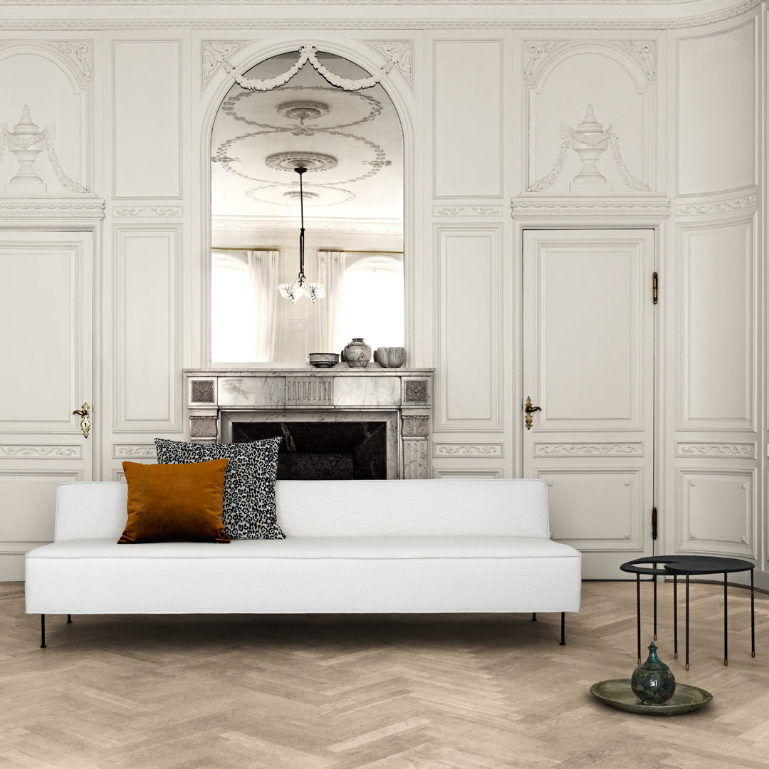 Modern white sofa with textured black and gold accent pillows, displayed in an elegant, neutral-toned room.