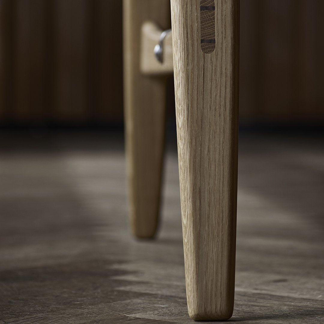 Light oak wood legs with a smooth finish and natural grain pattern on a dark wooden floor.