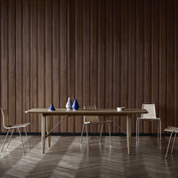 Natural wood dining table with light brown finish, complemented by blue and white decorative vases against a dark wooden wall.