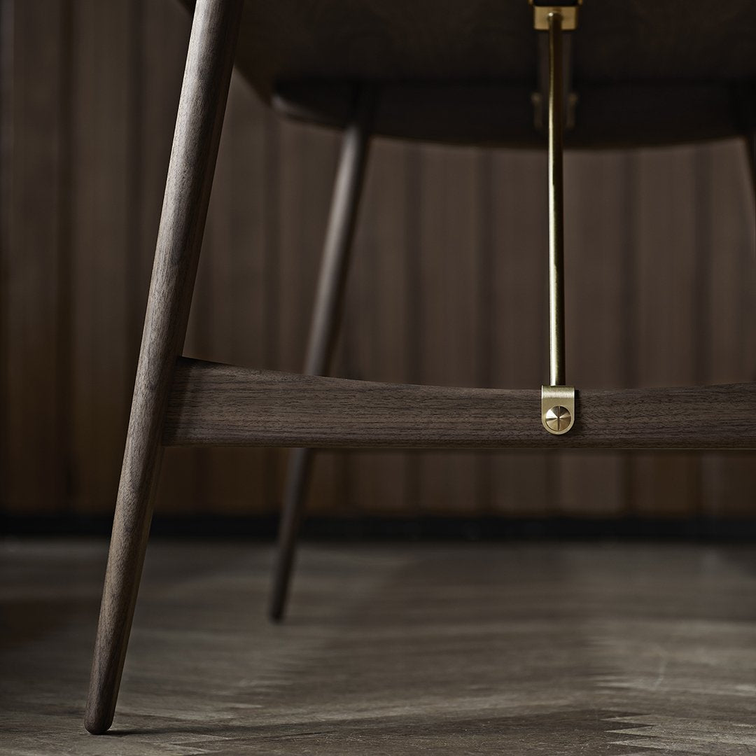 Dark wood chair with sleek lines and brass accents, showcasing a modern, minimalistic design.