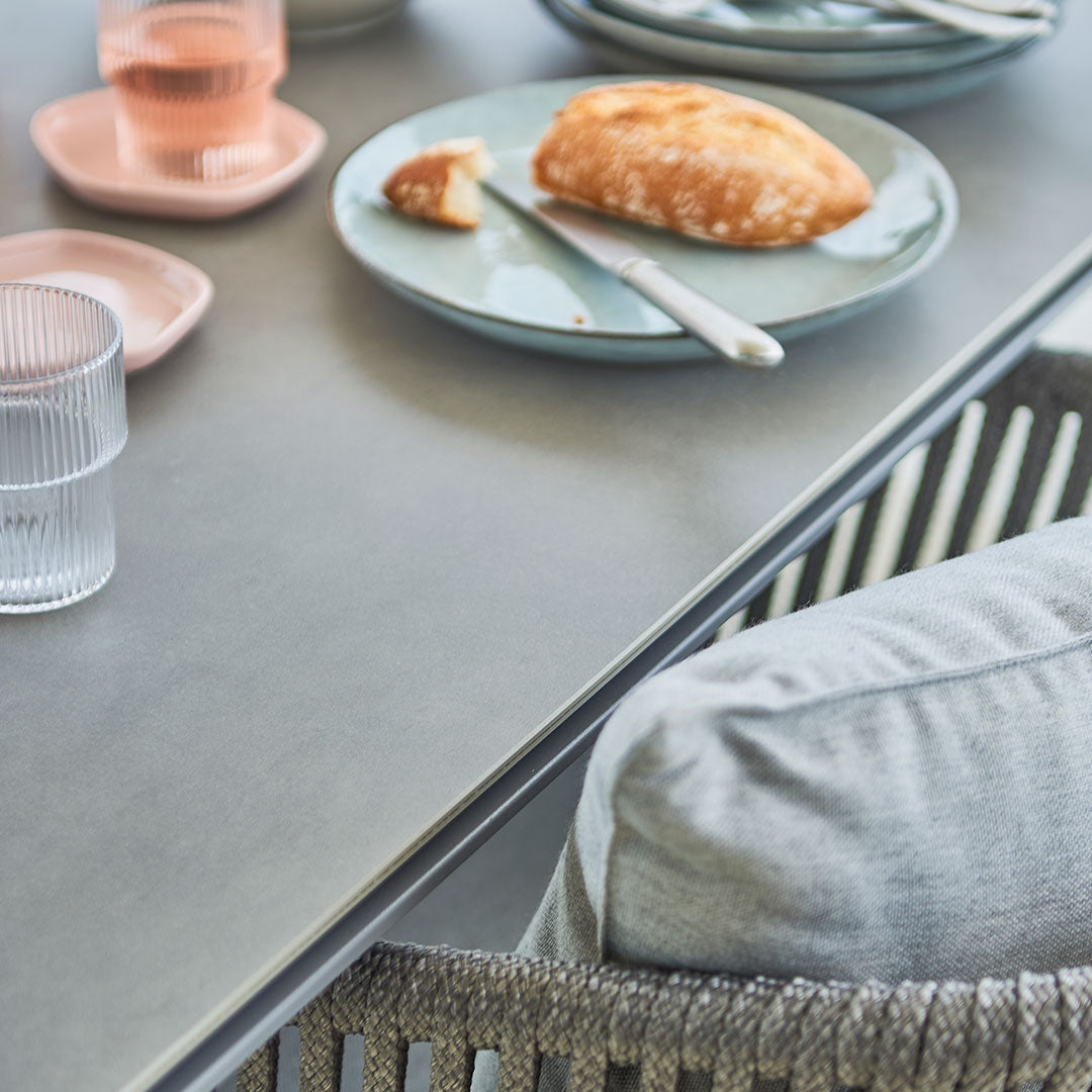 "Soft grey table with textured patterns, light blue dish, pink plates, and clear glassware, creating a cozy dining scene."
