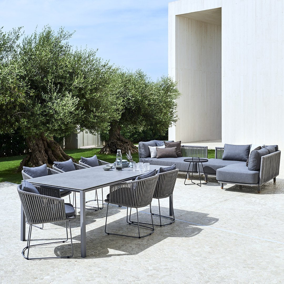 "Modern outdoor dining set featuring gray wicker chairs and a sleek gray table against a bright, sunny background."