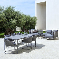 "Modern outdoor dining set featuring gray wicker chairs and a sleek gray table against a bright, sunny background."