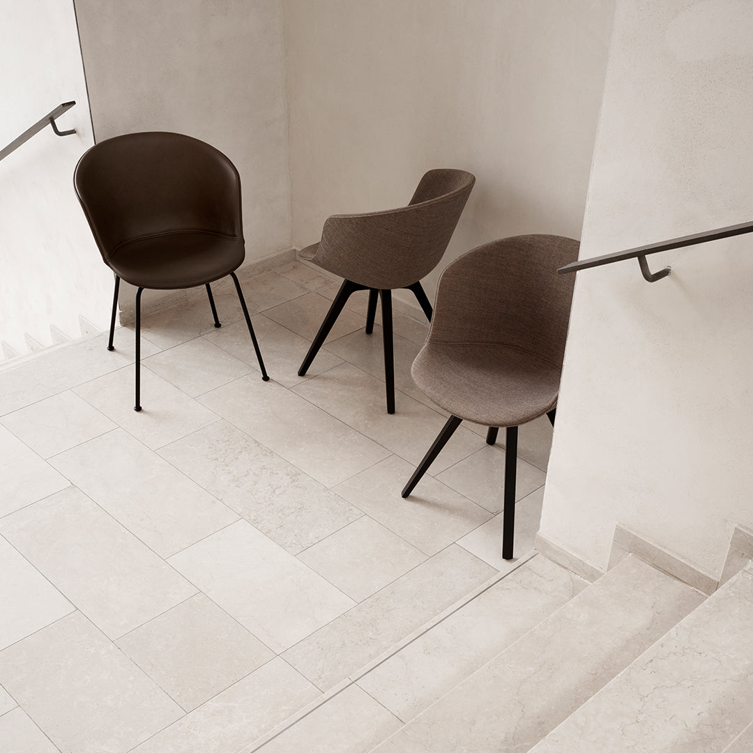 Brown fabric chairs with curved backs and sleek black legs, arranged on a light-colored tiled floor.