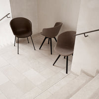 Brown fabric chairs with curved backs and sleek black legs, arranged on a light-colored tiled floor.