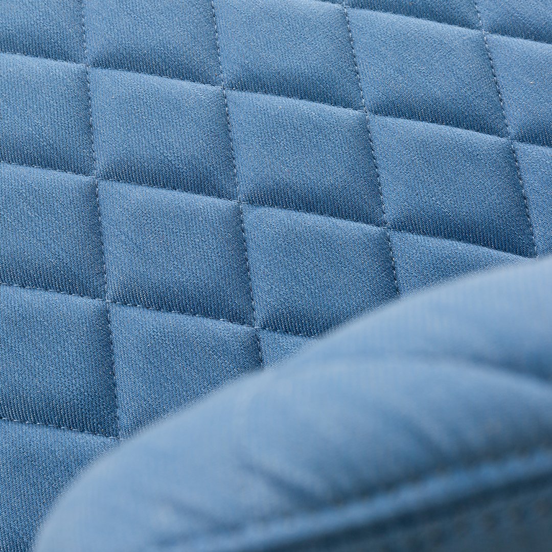 Textured quilted pattern in soft blue fabric, featuring diamond shapes and a smooth finish.