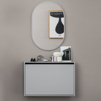 Gray wall-mounted storage unit with sleek lines, paired with a round mirror and minimalist decor against a beige wall.