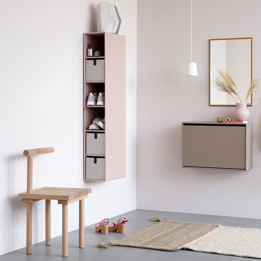 Stylish pink and gray storage cabinet with geometric patterns, complemented by a light wooden chair and neutral rug.