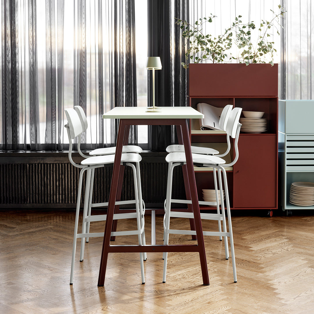"White bar stools with a wooden brown table, set against a backdrop of sleek black curtains and earthy tones."