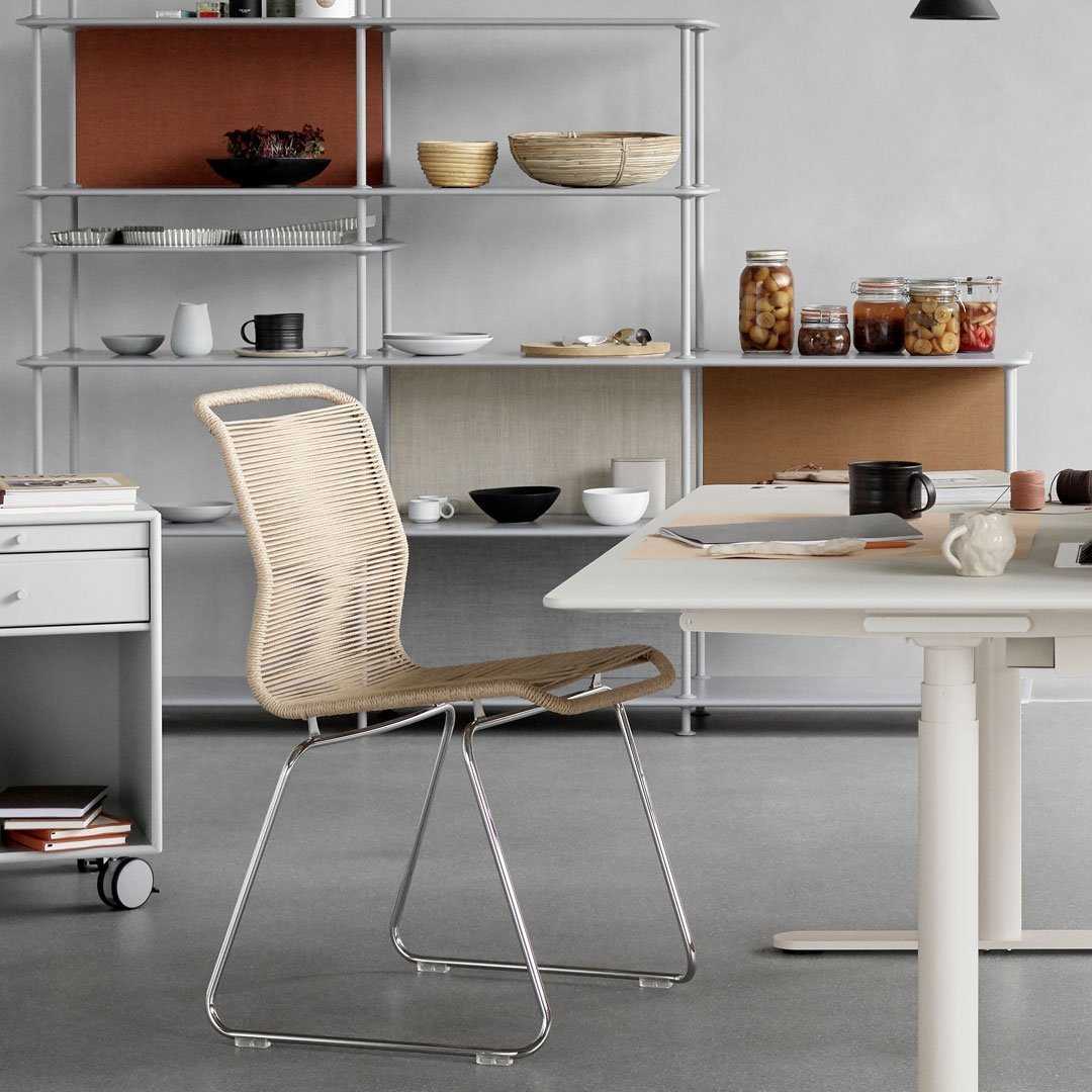 Modern chair featuring a natural wood finish and sleek chrome legs, set against a minimalist gray and earthy backdrop.