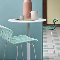 Aqua chairs and soft pastel-hued tableware create a fresh, modern dining scene with geometric floor patterns.