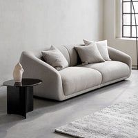 Light gray modern sofa with smooth, rounded edges and throw pillows, set against a minimalist backdrop.