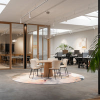 Round rug featuring soft pastel colors and abstract patterns, enhancing a modern office space.