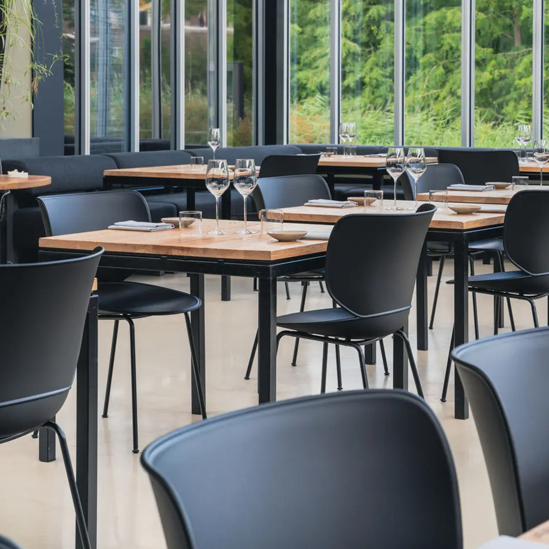 Modern black chairs with wooden tabletops in a stylish, minimal dining space, featuring a sleek color contrast.