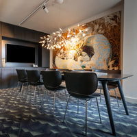 "Contemporary dining room with black chairs, colorful patterned wall art, and geometric blue-gray carpet."