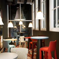 "Colorful dining area with red, blue, and green chairs, patterned rug, and stylish pendant lights."