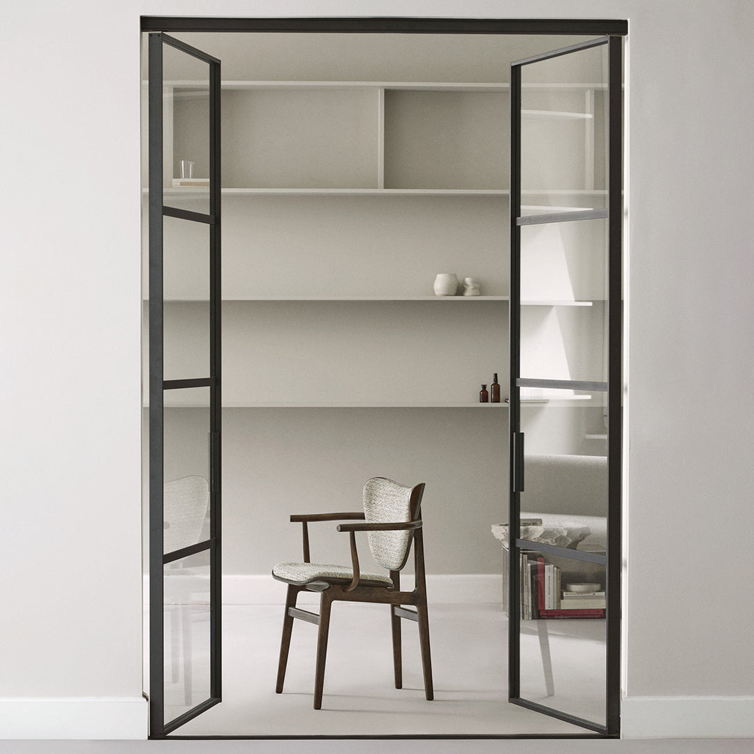 Black metal frame door with glass panels, showcasing a minimalist interior in soft neutral tones.