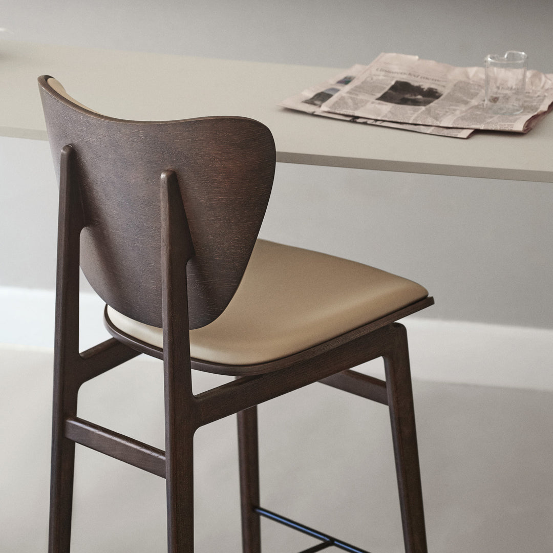 Brown wooden chair with a beige cushioned seat against a minimalist background. Stylish and modern design.